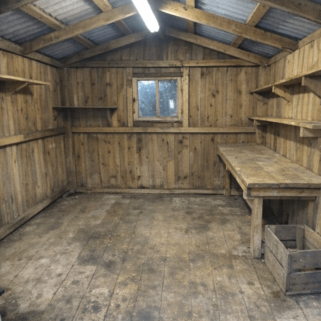 Kleiner Gartenschuppen mit freiem Eingang und gestapelten Holzbrettern zur Abfuhr